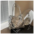 Nahaufnahme einer silbernen Pailletten-Tasche mit geflochtenem Ledergriff und Modeschild - Silber