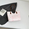 Borsa tote in pelle bianca con graffiti rosa e manici marroni su una giacca grigia - Rosa Senza Pendente