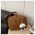 Close-up of caramel brown retro bowling bag on soft knit fabric with cloud pendant - Brown (Includes Cloud Charm)