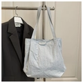Detalle del bolso tote de nailon gris claro con etiqueta de moda sobre fondo blanco - Azul
