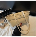 Detailed macro shot of cream faux leather shoulder bag with silver hardware and laptop - Off White