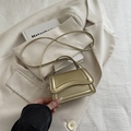 Mini champagne gold crossbody bag with top handle and sleek metallic finish on blazer background - Gold
