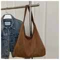 Detail of a large brown suede tote bag on a display rack with a denim jacket background - Brown