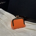 Mini orange kiss-lock wallet in lychee grain leather on elegant white silk background - Orange