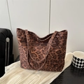 Large vintage leopard print suede shoulder bag for women on a dark wooden surface - Brown