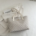 Elegant off-white tote bag with all-over M-letter pattern and gold metal detail. - White