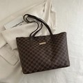 Brown monogram tote bag with gold logo plate and leather handles on cream blazer background - Brown