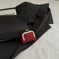 Mini red litchi leather coin purse with golden metal kiss-lock clasp in a flat lay view - Red