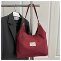 Detail of burgundy suede tote bag featuring a white fashion logo patch and long strap - Red