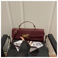 Détail du sac à main bordeaux à motif crocodile avec fermoir doré sur chaise en cuir - Rouge