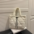 White heart-quilted dumpling handbag with drawstring closure on a book backdrop - White