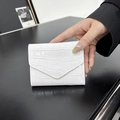 Portafoglio a busta bianco lucido in pelle verniciata coccodrillo tenuto in mano - Bianco