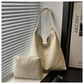 Detalle del bolso tote blanco crema con textura y neceser junto a una ventana soleada - Blanco Roto