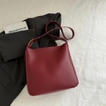 Bolso cubo burdeos minimalista con correa ajustable sobre un blazer negro - Rojo