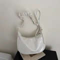 Bolso tipo dumpling blanco crema con correa plisada presentado sobre una revista chic - Blanco