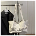 Dettaglio borsa tote bianca in pelle con cinturini con occhielli argento e tracolla regolabile - Bianco