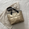 Borsa tote trapuntata dorata con tracolla nera in un contesto moderno chic - Oro