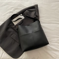 Minimalist black leather bucket bag with wide strap on elegant grey blazer background - Black