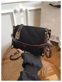Detail of vintage quilted fabric with brown leather trim and golden metal lock hardware - Black