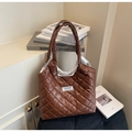 Detail einer braunen Stepp-Tote-Bag mit Glanzeffekt und Fashion Instinct Label auf schwarzem Sitz - Champagner