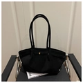 Detail of black matte tote bag with golden buckle and strap on a modern chair - Black