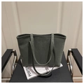 Detail der dunkelgrünen Shopper-Tasche mit Leopardenmuster auf einem Magazin und Stuhl - Grün