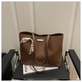 Detalle de bolso tote marrón de cuero sintético con pañuelo de seda y elegantes adornos - café