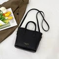 Bolso tipo cubo minimalista en cuero negro con logo dorado y bandolera - Negro