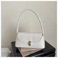 Detalle de bolso de hombro en cuero blanco con hebilla dorada sobre unos libros - Blanco