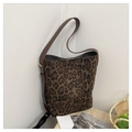 Gros plan d'un grand sac cabas léopard avec bandoulière en daim marron sur surface tressée - café