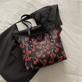 Schwarze Tragetasche mit Kirschmuster und goldenem Fashion-Text auf Leder-Oberfläche - Schwarz
