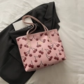 Rosa Tote Bag mit Kirschdruck und Litschi-Textur auf schwarzem Blazer-Hintergrund - Rosa