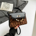 Modische Handtasche mit Leopardenmuster, schwarzen Lederakzenten und goldenem Drehschloss - Schwarz