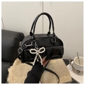 Detail der schwarzen Lackleder Boston Bag mit Perlen-Schleifen-Anhänger auf Strick - Schwarz