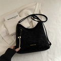Elegante borsa tote in pelle opaca nera con scritte dorate su un blazer bianco - Nero