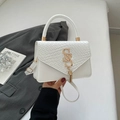 White patchwork crossbody bag with gold logo, woven texture, and tassel detail - White