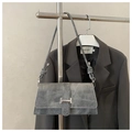 Detail of grey suede shoulder bag with knot strap and silver buckle on a suit hanger - Gray