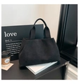 Dettaglio della borsa tote in pelle scamosciata nera con tracolla larga su scrivania - Nero
