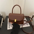 Braune Vintage-Handtasche aus Leder mit goldenem Verschluss vor stilvollem Studio-Hintergrund - Braun