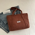 Braune Cord-Tragetasche mit Fashion-Instinct-Label auf ästhetischem Vintage-Hintergrund - Braun
