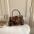 Close-up of retro brown plaid fabric and leather flap bag with large gold metal buckle - Brown