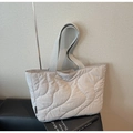 Close-up of a grey quilted tote bag featuring a brand tag on its soft nylon surface - Gray
