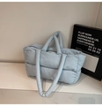 Close-up of light blue quilted puffer tote bag with padded texture and dual handles - Blue