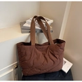 Dettaglio della borsa tote in nylon trapuntato marrone con cuciture a onde e manico largo - caffè