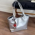 Primer plano de bolso tote plateado metalizado con correas finas y colgante de estrella roja - Plateado
