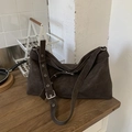 Detailaufnahme der braunen Veloursleder-Tasche mit Metallösen und verstellbarem Riemen - Braun