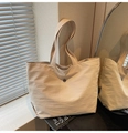Détail d'un sac cabas minimaliste en toile beige avec emblème en métal et lumière naturelle - Blanc Cassé