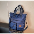 Detail of navy nylon tote bag showing functional pockets and leather bicycle logo - Blue