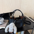 Close-up of black lychee grain leather bucket bag with a plush rabbit charm and gold hardware - Black with Pendant