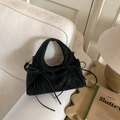 Dettaglio di borsa scamosciata nera con fiocchi e fibbie in argento su divano bianco - Nero
